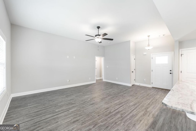 unfurnished living room featuring wood finished floors, baseboards, and a ceiling fan