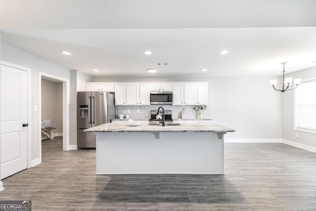 kitchen with stainless steel appliances, a center island with sink, baseboards, white cabinets, and recessed lighting