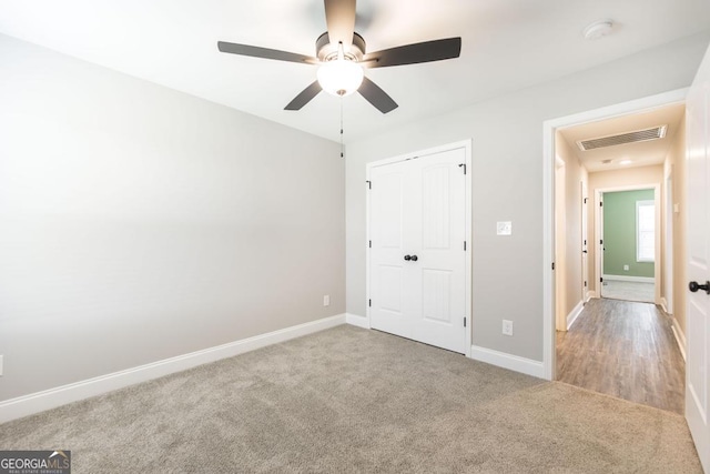 unfurnished bedroom with carpet floors, a closet, baseboards, and a ceiling fan
