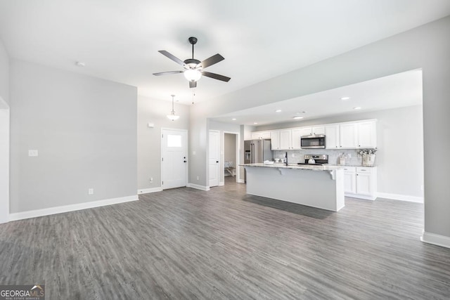 unfurnished living room with wood finished floors, ceiling fan, baseboards, and recessed lighting