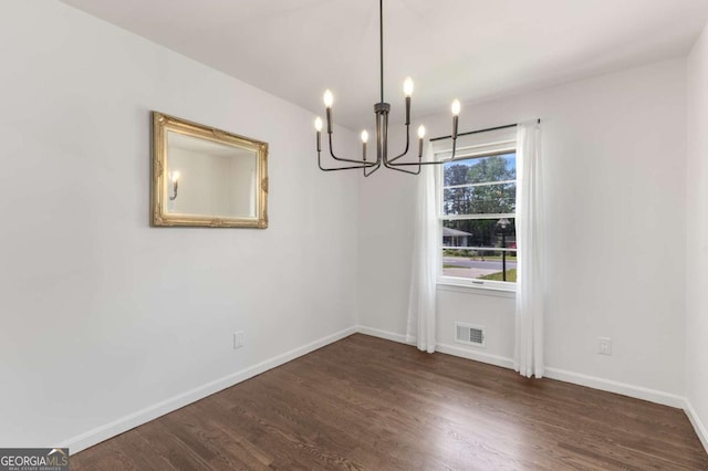 unfurnished dining area featuring a chandelier, dark wood-type flooring, and baseboards