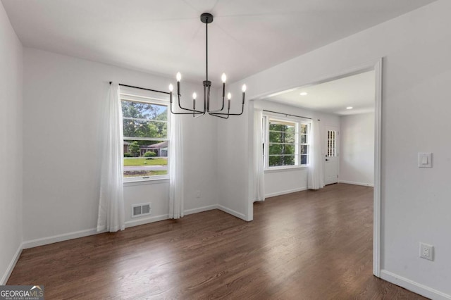 unfurnished dining area with a chandelier, wood finished floors, and baseboards