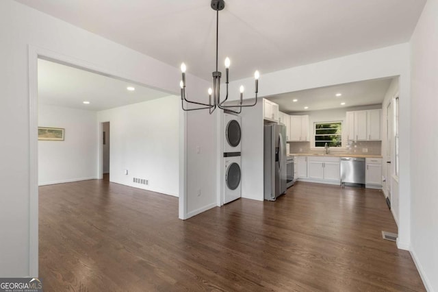 kitchen with stainless steel appliances, open floor plan, stacked washer / drying machine, a sink, and a chandelier