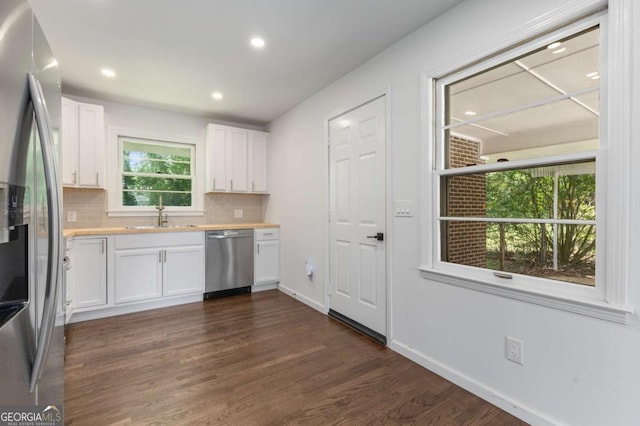 kitchen featuring stainless steel appliances, a sink, backsplash, dark wood-style flooring, and recessed lighting