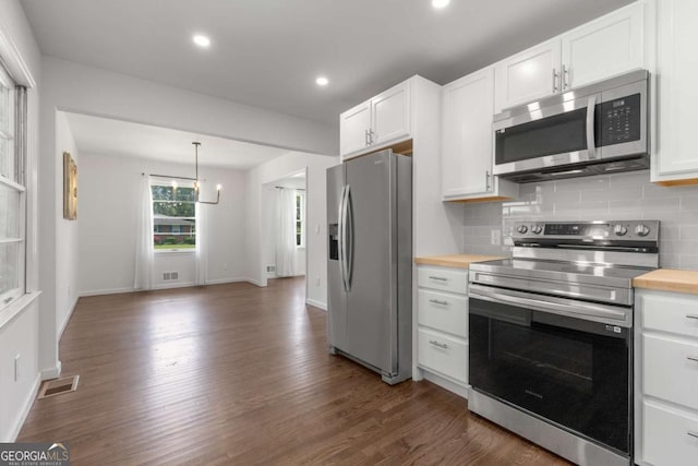 kitchen with appliances with stainless steel finishes, dark wood-style flooring, tasteful backsplash, white cabinets, and butcher block counters