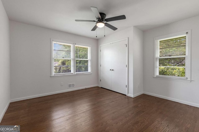 unfurnished bedroom with dark wood-style flooring, baseboards, and a ceiling fan
