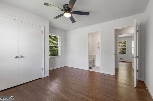unfurnished bedroom with wood finished floors, baseboards, a closet, and connected bathroom