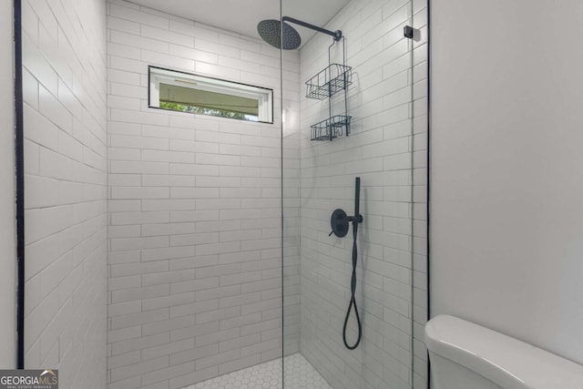 bathroom with a tile shower and toilet