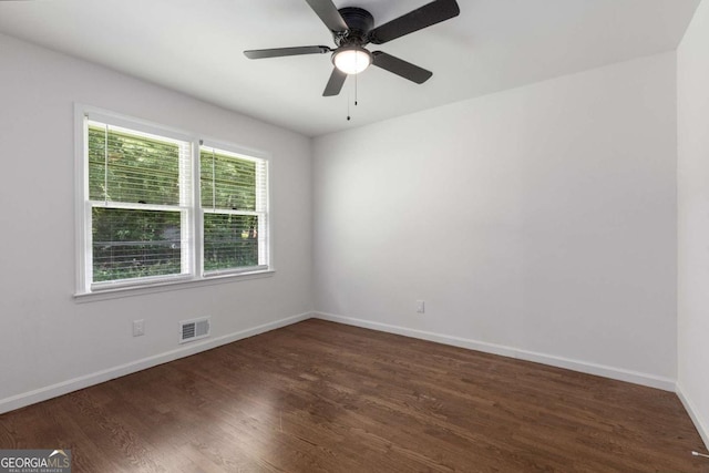 empty room featuring dark wood-style flooring, baseboards, and ceiling fan