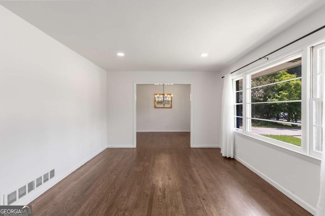 empty room featuring a chandelier, wood finished floors, baseboards, and recessed lighting