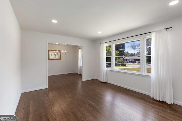 spare room featuring a chandelier, wood finished floors, recessed lighting, and baseboards