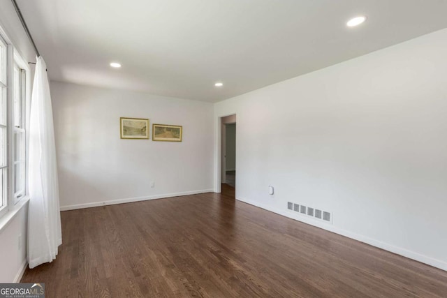 empty room with dark wood finished floors, baseboards, and recessed lighting