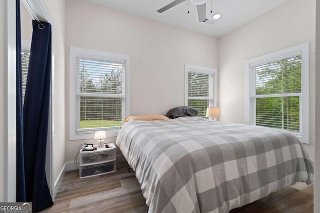 bedroom with wood finished floors, multiple windows, baseboards, and ceiling fan