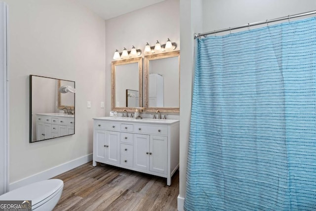 bathroom with wood finished floors, toilet, baseboards, double vanity, and a shower with curtain