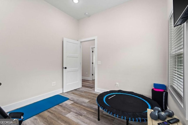 exercise area with wood finished floors, baseboards, and recessed lighting