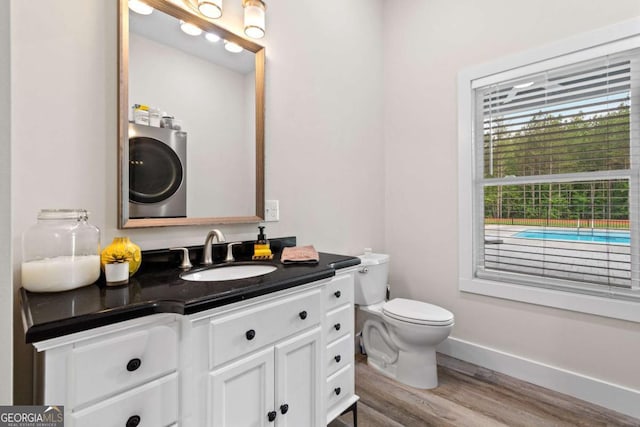 bathroom with wood finished floors, vanity, toilet, and baseboards