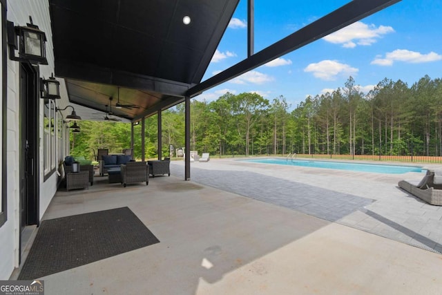 view of patio featuring outdoor lounge area, a ceiling fan, and a wooded view