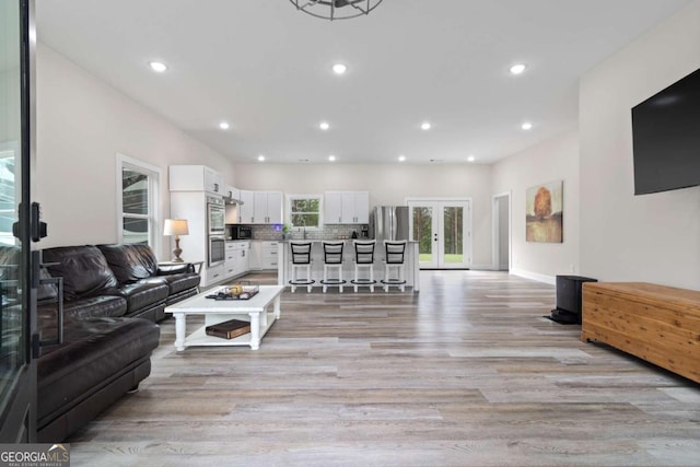 living room with french doors, light wood-type flooring, recessed lighting, and baseboards