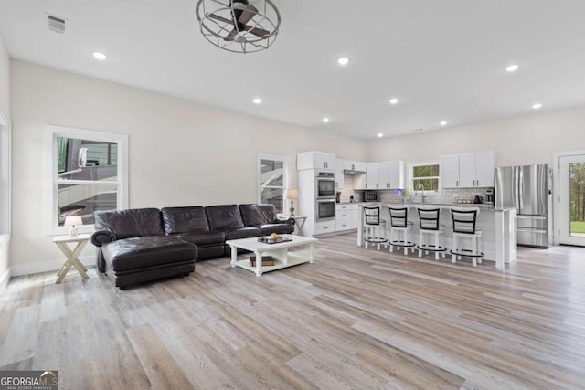 living room featuring light wood-type flooring, recessed lighting, a ceiling fan, and baseboards