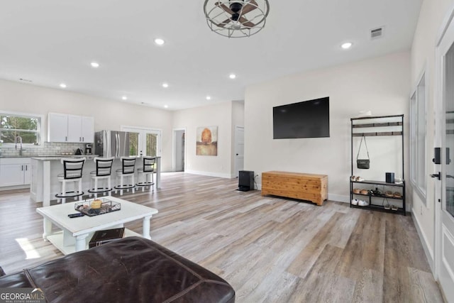 living area with healthy amount of natural light, light wood-type flooring, and recessed lighting