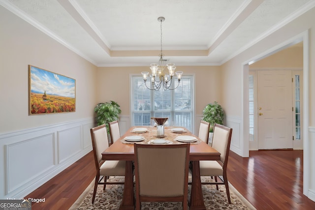 954 Josie Ct, Lawrenceville, GA 30045 - dining room featuring a tray ceiling, dark wood-type flooring, a chandelier, a decorative wall, and a wainscoted wall