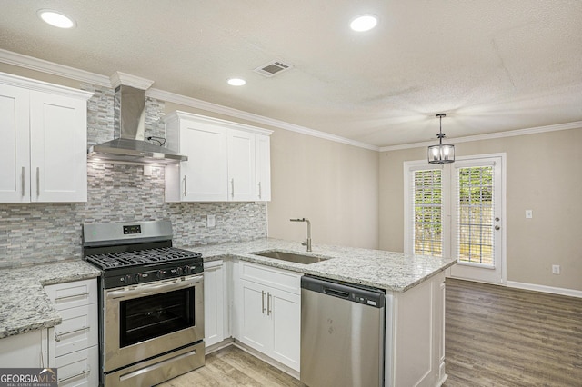 50 Fieldview Ln, Covington, GA 30016 - kitchen with appliances with stainless steel finishes, wall chimney range hood, a peninsula, light wood finished floors, and white cabinetry