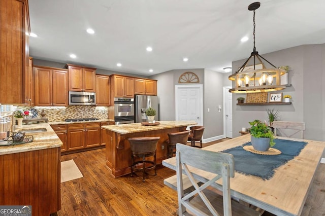 4840 Spring Park Cir, Suwanee, GA 30024 - kitchen with stainless steel appliances, a sink, brown cabinets, a center island, and dark wood-style flooring