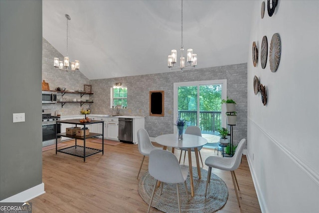 dining area with a chandelier, vaulted ceiling, and light wood finished floors