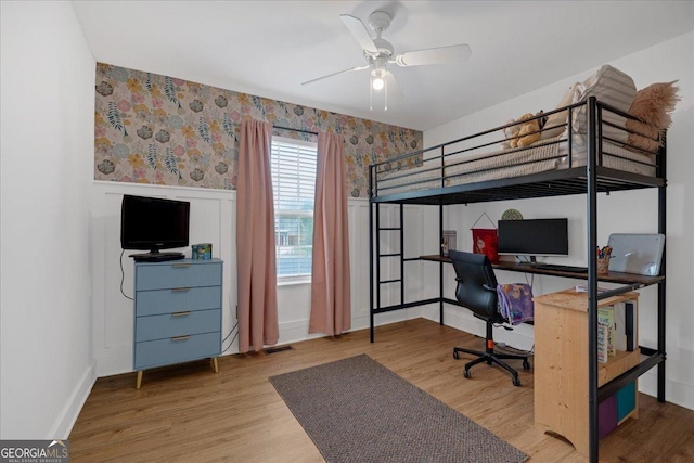 bedroom with wallpapered walls, a desk, wood finished floors, and baseboards