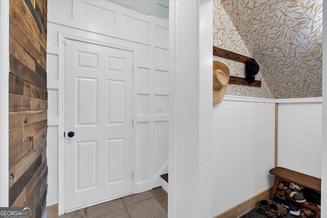 bathroom with wallpapered walls, tile patterned floors, and wainscoting