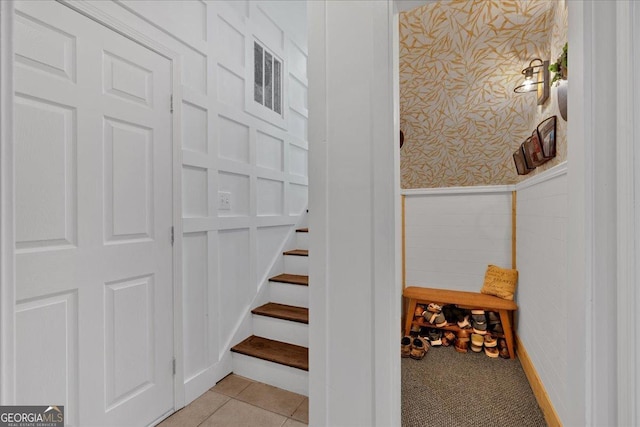 stairway with wainscoting and wallpapered walls