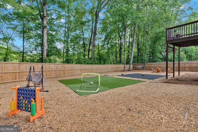 view of jungle gym with a putting green, a fenced backyard, and a wooden deck