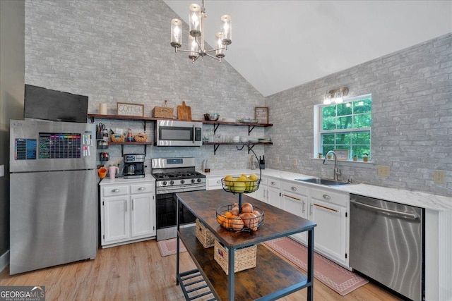 kitchen with appliances with stainless steel finishes, a sink, vaulted ceiling, open shelves, and white cabinetry
