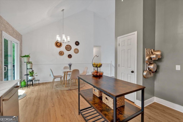 dining room with high vaulted ceiling, light wood-style flooring, a chandelier, and baseboards