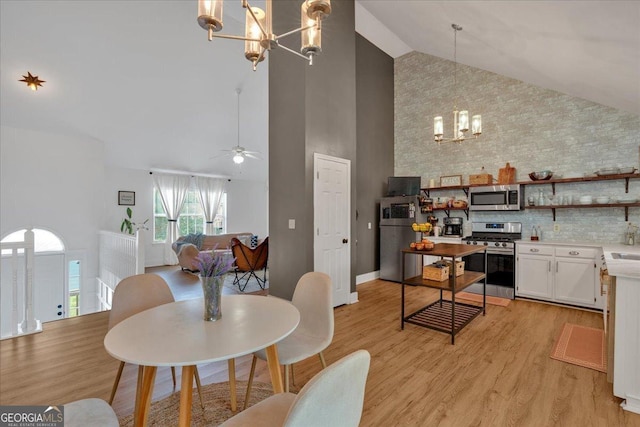 dining area with a chandelier, high vaulted ceiling, light wood-type flooring, and a ceiling fan