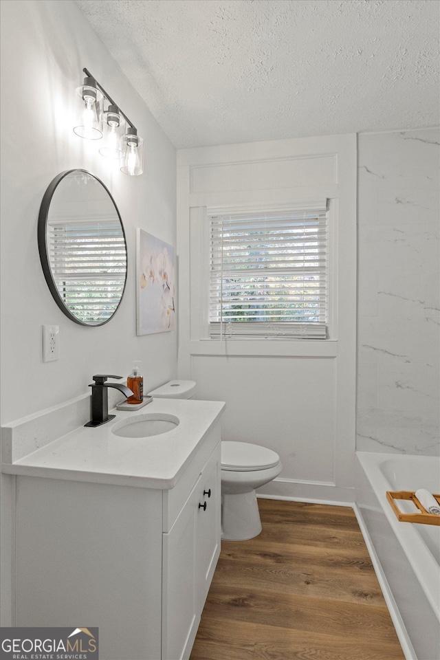 2378 Green Forrest Dr, Decatur, GA 30032 - bathroom featuring a textured ceiling, wood finished floors, vanity, and toilet