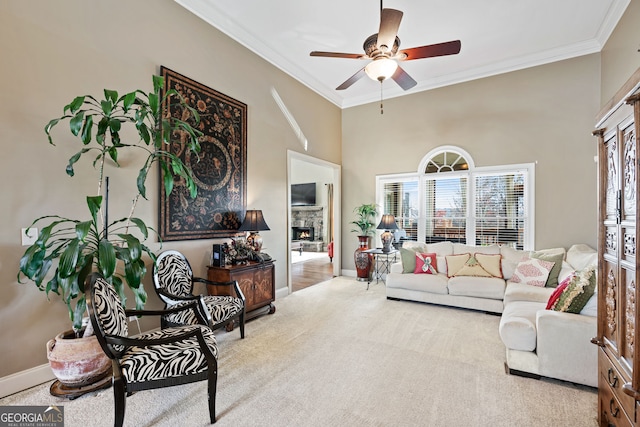 2041 Democracy Dr, Buford, GA 30519 - carpeted living room featuring crown molding, ceiling fan, a fireplace, baseboards, and a towering ceiling