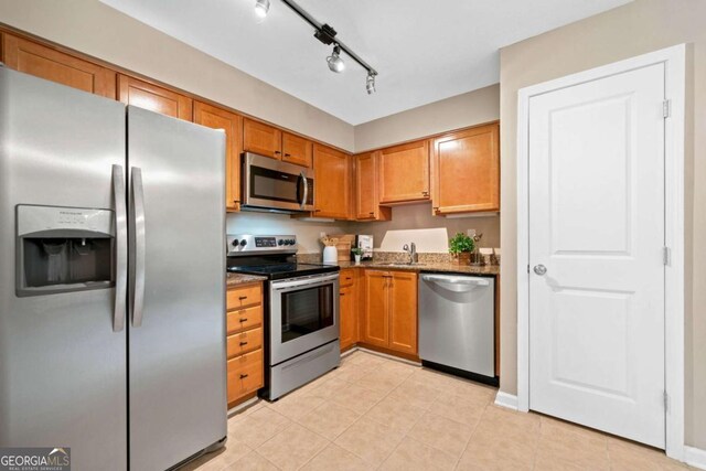 3200 Seven Pines Ct Unit 103, Atlanta, GA 30339 - kitchen featuring appliances with stainless steel finishes, a sink, dark stone countertops, light tile patterned floors, and brown cabinetry