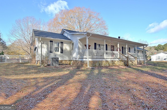 single story home featuring covered porch, cooling unit, and fence