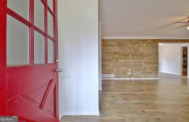 foyer featuring ceiling fan, wood finished floors, and wood walls