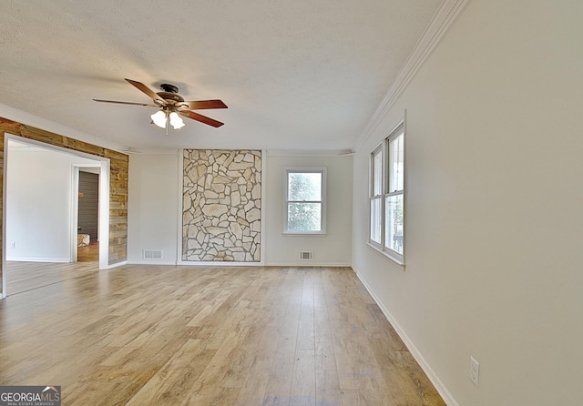 unfurnished room with ornamental molding, ceiling fan, light wood-style flooring, a textured ceiling, and baseboards