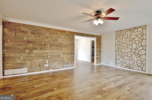 spare room featuring ceiling fan, ornamental molding, wood finished floors, baseboards, and a textured ceiling