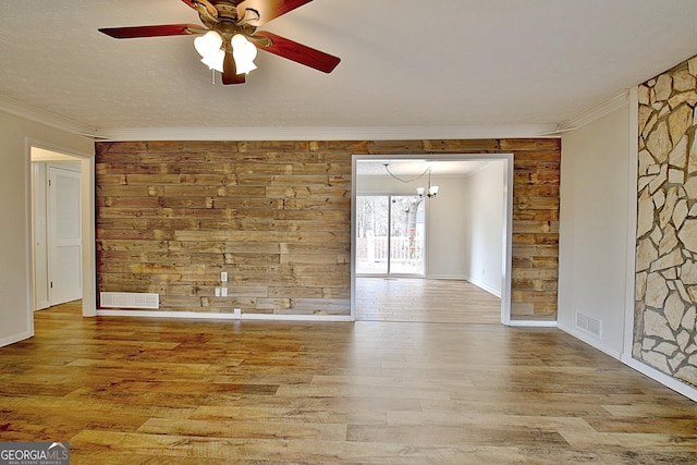 spare room with a ceiling fan, crown molding, wood finished floors, a chandelier, and baseboards