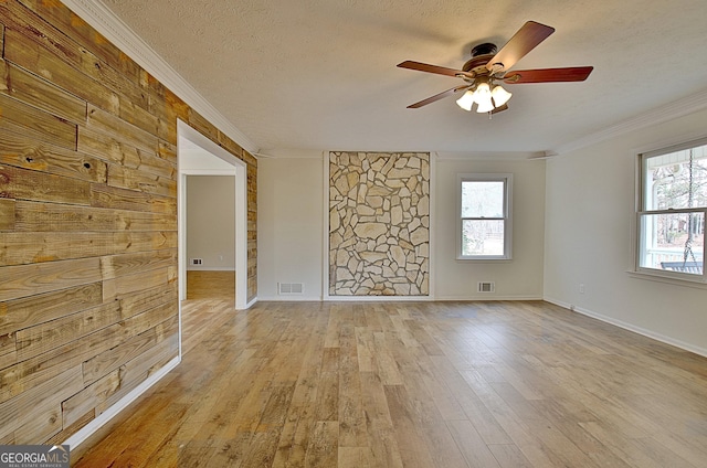 unfurnished room featuring crown molding, hardwood / wood-style flooring, a ceiling fan, a textured ceiling, and baseboards
