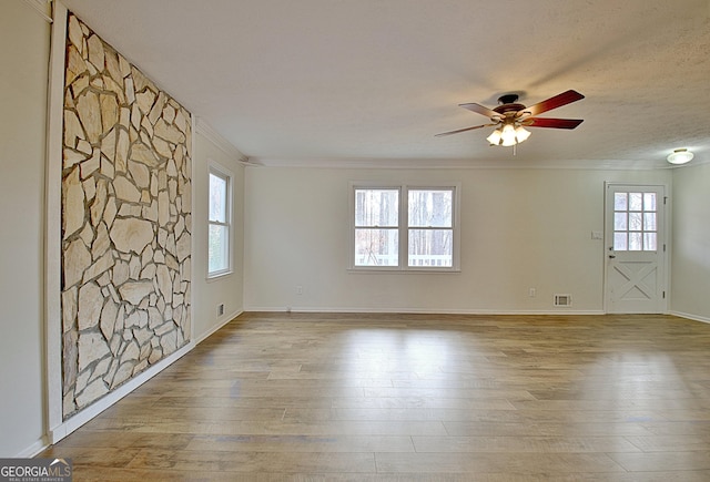 unfurnished room featuring crown molding, wood-type flooring, a ceiling fan, and baseboards