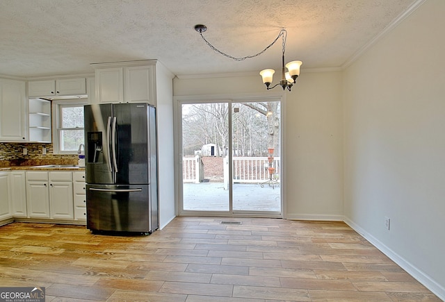 kitchen featuring stainless steel refrigerator with ice dispenser, open shelves, white cabinetry, a chandelier, and crown molding