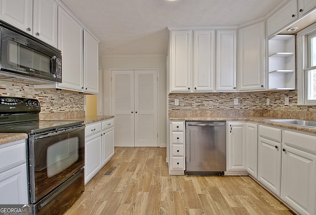 kitchen with black appliances, white cabinetry, ornamental molding, light wood-style flooring, and backsplash
