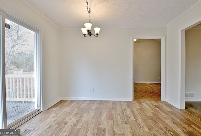 spare room featuring a chandelier, light wood finished floors, ornamental molding, baseboards, and a textured ceiling
