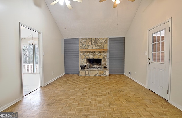 unfurnished living room with vaulted ceiling, a ceiling fan, baseboards, and a stone fireplace
