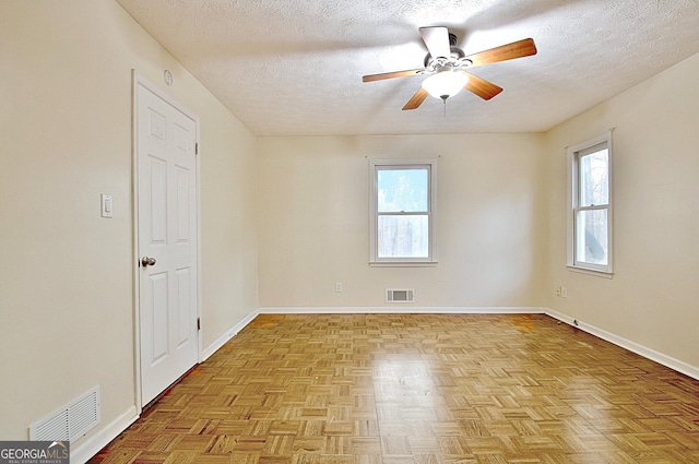 unfurnished room with healthy amount of natural light, ceiling fan, a textured ceiling, and baseboards